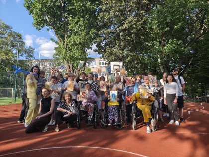 Na obrazku grupa młodzieży wraz z dziećmi i seniorami pozuje do zdjęcia