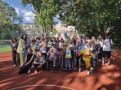 Na obrazku grupa młodzieży wraz z rodzinami i seniorami pozuje do zdjęcia