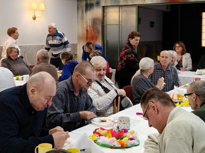 Starsze osoby spożywające posiłek przy stole w tle pomagający personel