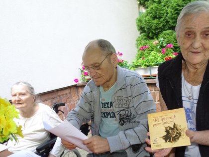 Seniorzy uczestniczący w spotkaniu poetyckim w ogrodzie sensorycznym