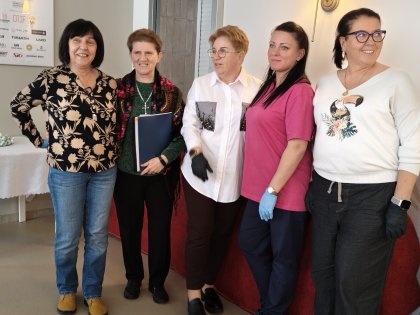 Zdjęcie pięciu pań w radosnym nastroju ,w tle sala z okienkiem kuchennym