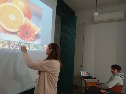 Na zdjęciu kobieta pokazuje na duży kolorowy ekran