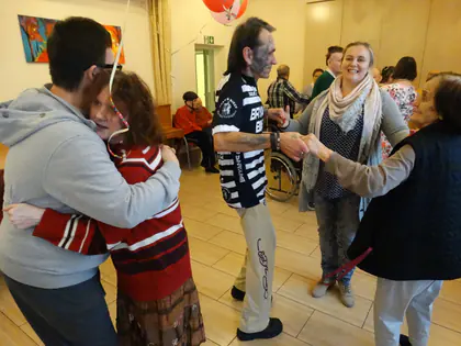 Uczestnicy zabawy tanecznej tańczą w parach w sali ozdobionej balonami