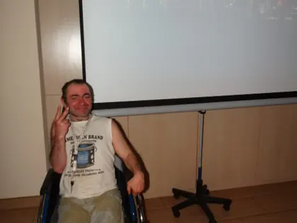 Mieszkaniec siedzi na wózku przed ekranem z transmisją z koncertu