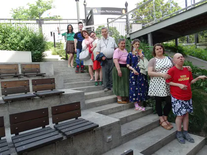 Grupa mieszkańców stoi na schodach z ławkami podczas spaceru po Starym Mieście
