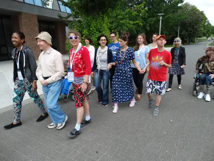 Mieszkańcy i wolontariusze idą razem alejką w parku