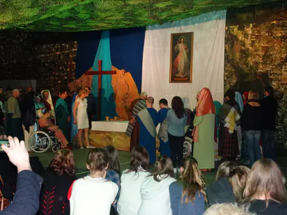 Uczestnicy misterium w strojach biblijnych przed ołtarzem z obrazem Jezusa Miłosiernego