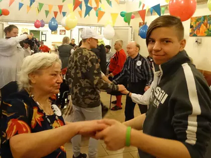 Mieszkanka tańczy z chłopcem na balu andrzejkowym w sali z balonami