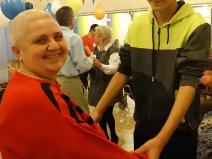 Uśmiechnięta mieszkanka w czerwonym swetrze tańczy z nastolatkiem
