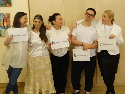 Aktorzy w białych strojach z kartkami #zrywamywięzy stoją objęci