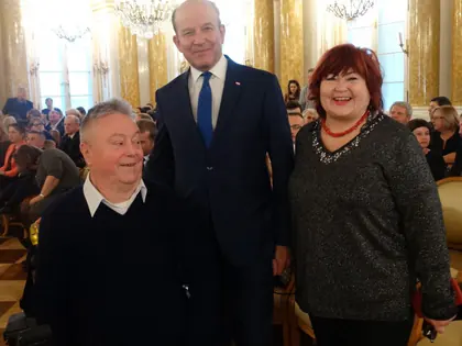 Mieszkaniec w ciemnym swetrze, mężczyzna w garniturze i kobieta w czarnej sukience w sali galowej
