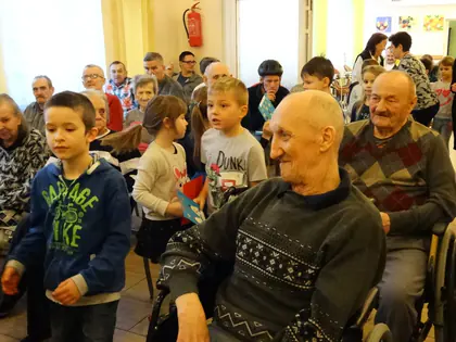 Przedszkolaki wręczają kartki mieszkańcom siedzącym w świetlicy
