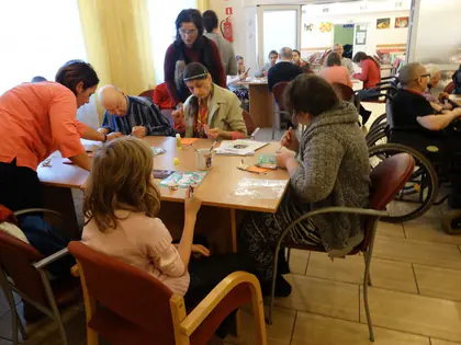 Mieszkańcy i goście wykonują kartki świąteczne przy wspólnym stole