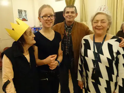 Mieszkanka w papierowej koronie, uczennica, mieszkaniec i mieszkanka pozują razem