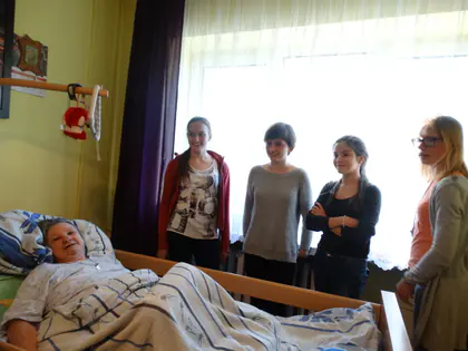 Młodzież wolontariusze odwiedza mieszkankę leżącą w łóżku