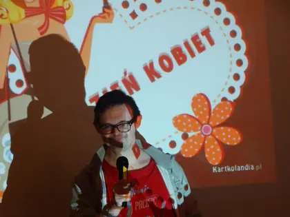 Mężczyzna z mikrofonem na tle slajdu z napisem Dzień Kobiet