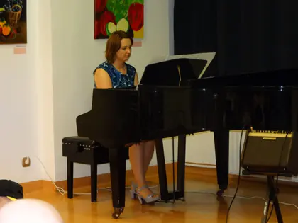 Pianistka gra na czarnym fortepianie w sali z obrazami
