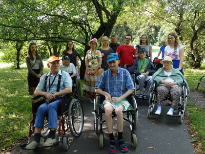 Mieszkańcy na wózkach z wolontariuszami wspólnoty w parku