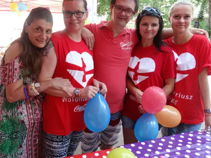Mieszkańcy i wolontariuszki z balonami przy stole w kropki