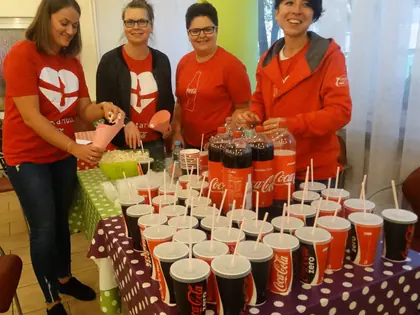 Wolontariuszki przy stole z kubkami napojów i popcornem przed seansem