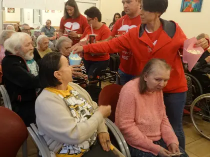 Wolontariusze rozdają popcorn mieszkańcom siedzącym na sali