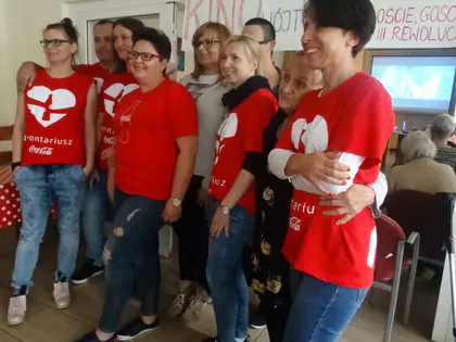 Grupa wolontariuszy w czerwonych koszulkach pozuje przy plakacie kina na Wójtowskiej