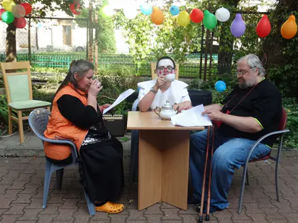 Mieszkańcy przy stoliku w ogrodzie z balonami podczas festynu