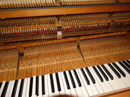 Odsłonięte wnętrze pianina z młoteczkami i strunami nad klawiaturą