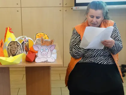 Mieszkanka w pomarańczowej kamizelce czyta tekst z kartki