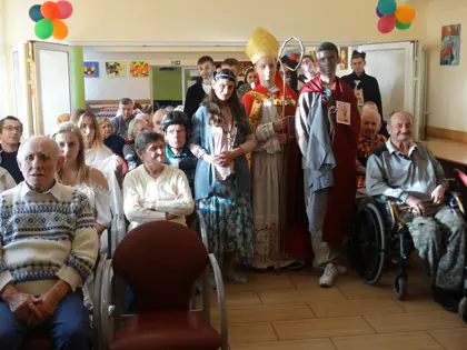 Uczestnicy balu przebrani za świętych, w tym biskupa w mitrze, pozują z mieszkańcami