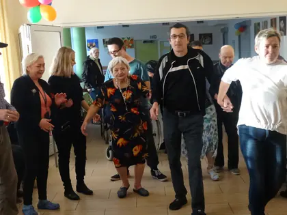 Mieszkańcy i goście tańczą w korowodzie w świetlicy