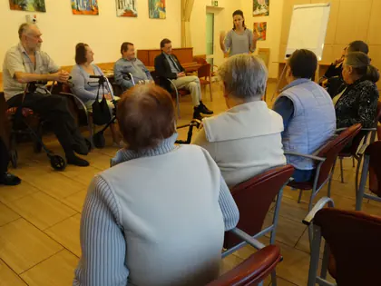 Mieszkańcy słuchają prowadzącej podczas spotkania w świetlicy