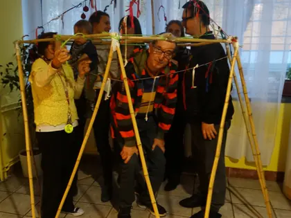 Mieszkańcy i dzieci stoją wewnątrz bambusowej konstrukcji ozdobionej wstążkami