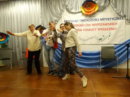 Mieszkańcy tańczą na scenie przed banerem Przeglądu Twórczości Artystycznej