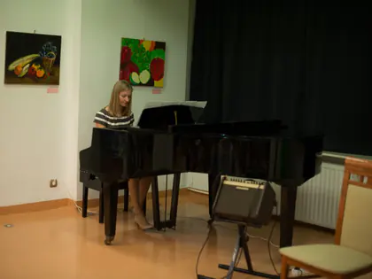Młoda pianistka gra przy fortepianie w sali wystawowej
