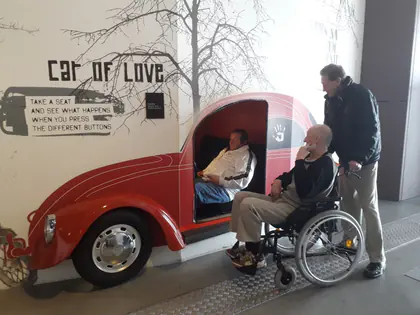Mieszkańcy siedzą w czerwonym samochodzie z napisem Car of Love w centrum nauki