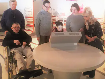 Uczestnicy wycieczki oglądają ekran na białym okrągłym stanowisku