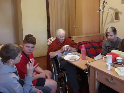 Chłopcy rozmawiają z mieszkanką na wózku przy stoliku w pokoju