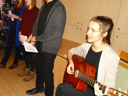 Młodzi kolędnicy śpiewają, dziewczyna gra na gitarze
