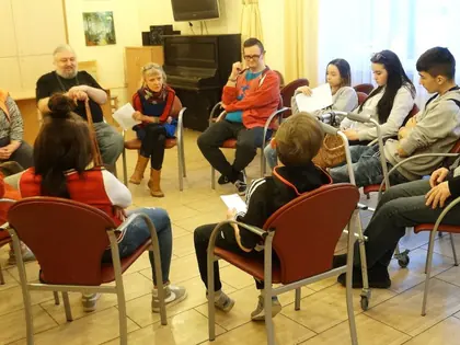 Mieszkańcy i młodzież siedzą w kręgu podczas warsztatów do spektaklu