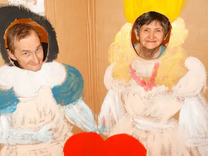 Mieszkańcy wyglądają przez otwory w malowanej dekoracji królowej i rycerza