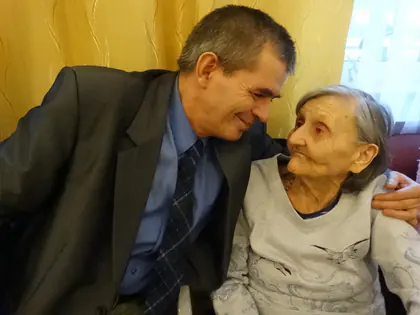 Mężczyzna w marynarce czule rozmawia ze starszą mieszkanką