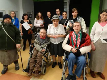Mieszkańcy, część na wózkach, pozują z muzykami zespołu po koncercie