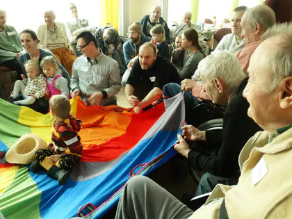 Dzieci i mieszkańcy trzymają tęczową chustę animacyjną