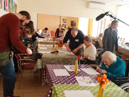 Operator kamery filmuje mieszkańców rysujących przy stołach