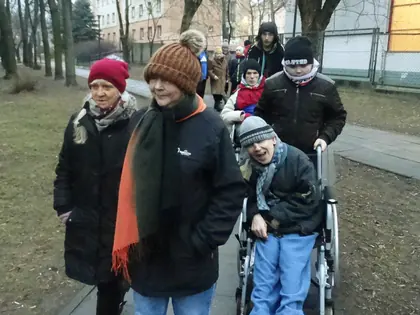 Mieszkańcy z opiekunami na zimowym spacerze alejką Nowego Miasta