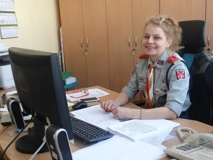 Pracownica Domu w mundurze harcerskim przy biurku z komputerem