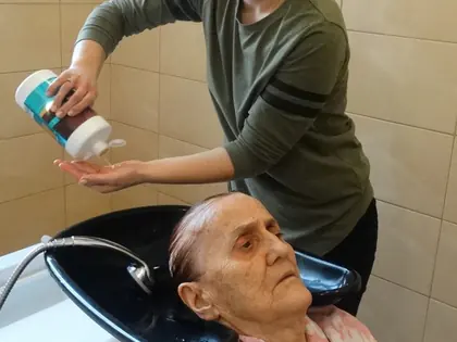 Fryzjerka myje włosy mieszkance przy umywalce fryzjerskiej