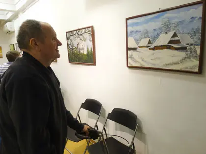 Mieszkaniec z balkonikiem ogląda pejzaż zimowy na wernisażu