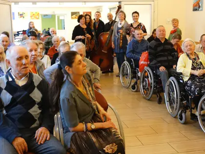 Mieszkańcy, część na wózkach, słuchają koncertu zespołu